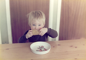 A young boy eating corn-on-the-cob at the kitchen table